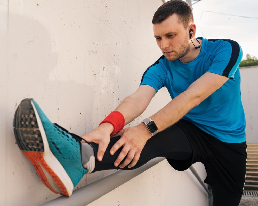 Hombre estirando mostrando una zapatilla de running ideal para un entrenamiento hibrido